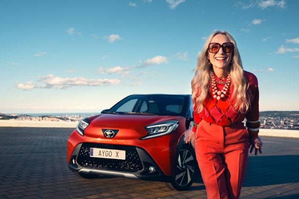 Chili Red Aygo X parked with female model in foreground